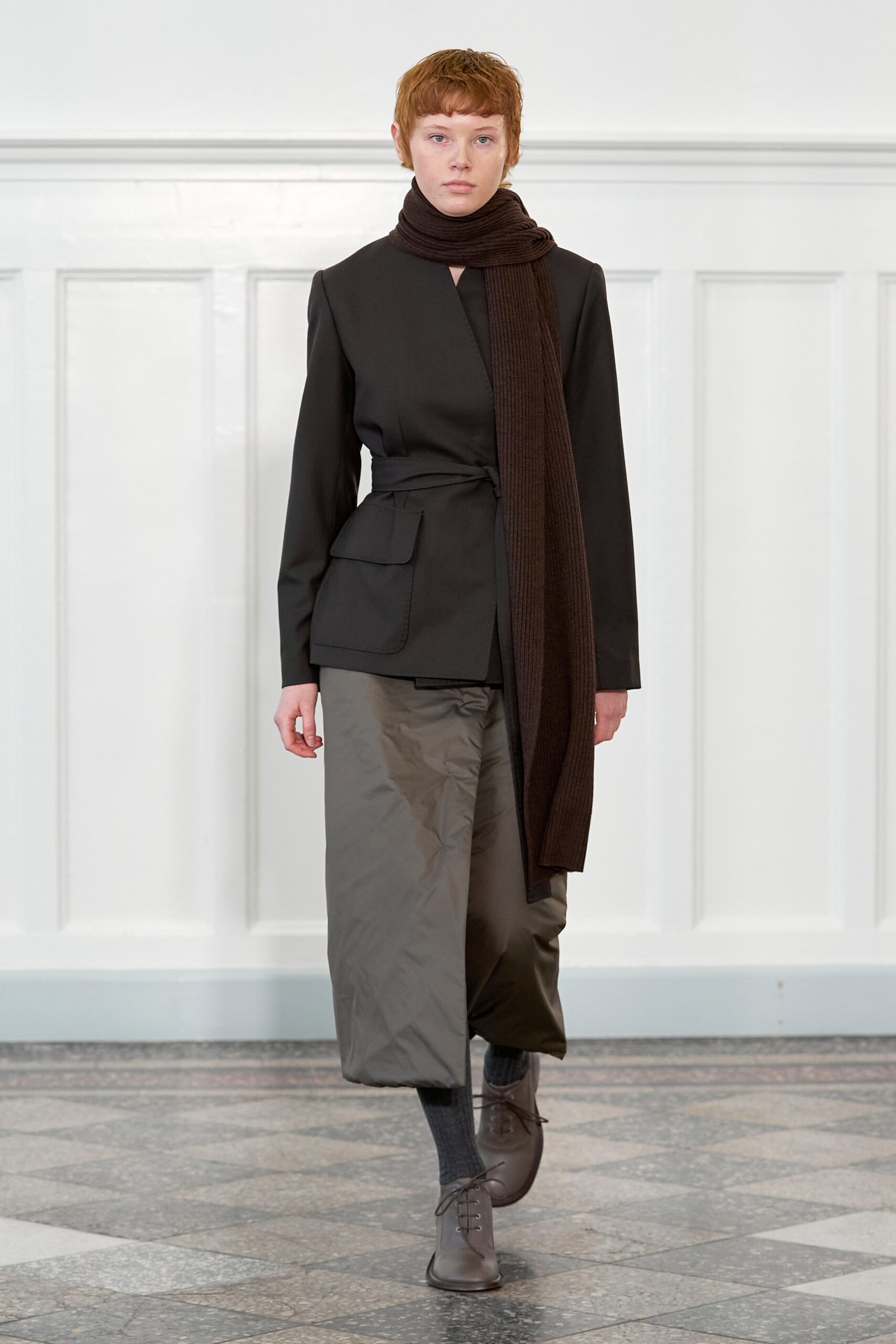 A relaxed black jacket with long sleeves, paired with gray pants and a scarf.