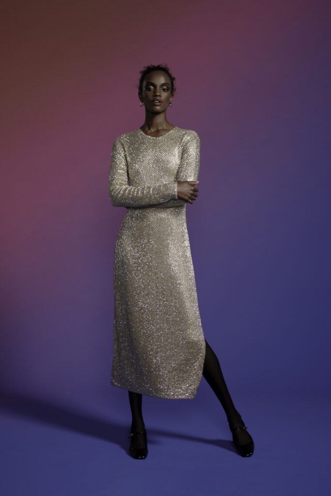 A fitted gold sequin dress with long sleeves and a crew neckline, featuring a straight-leg silhouette.