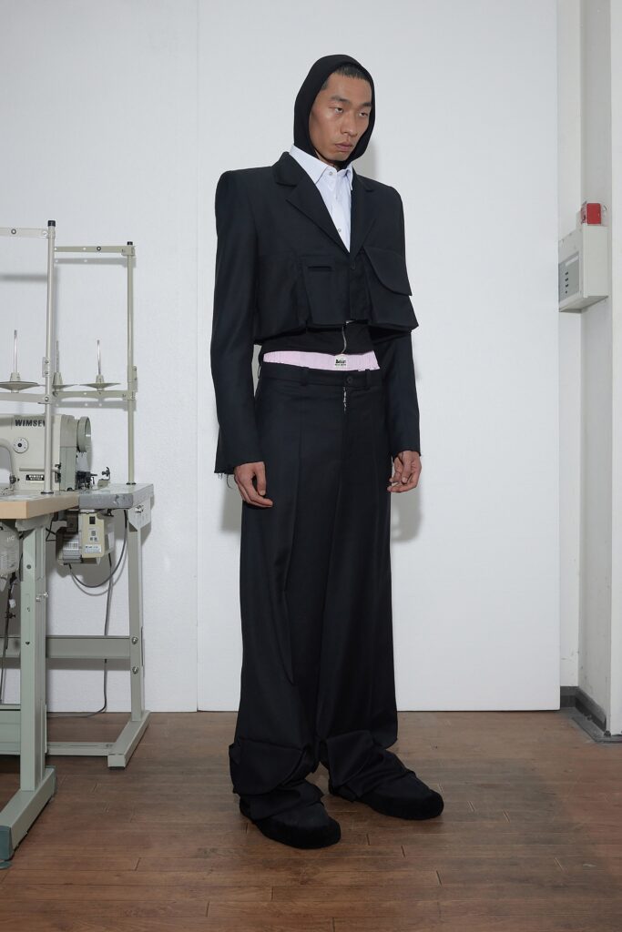 A relaxed black jacket with long sleeves and asymmetric design paired with matching pants.