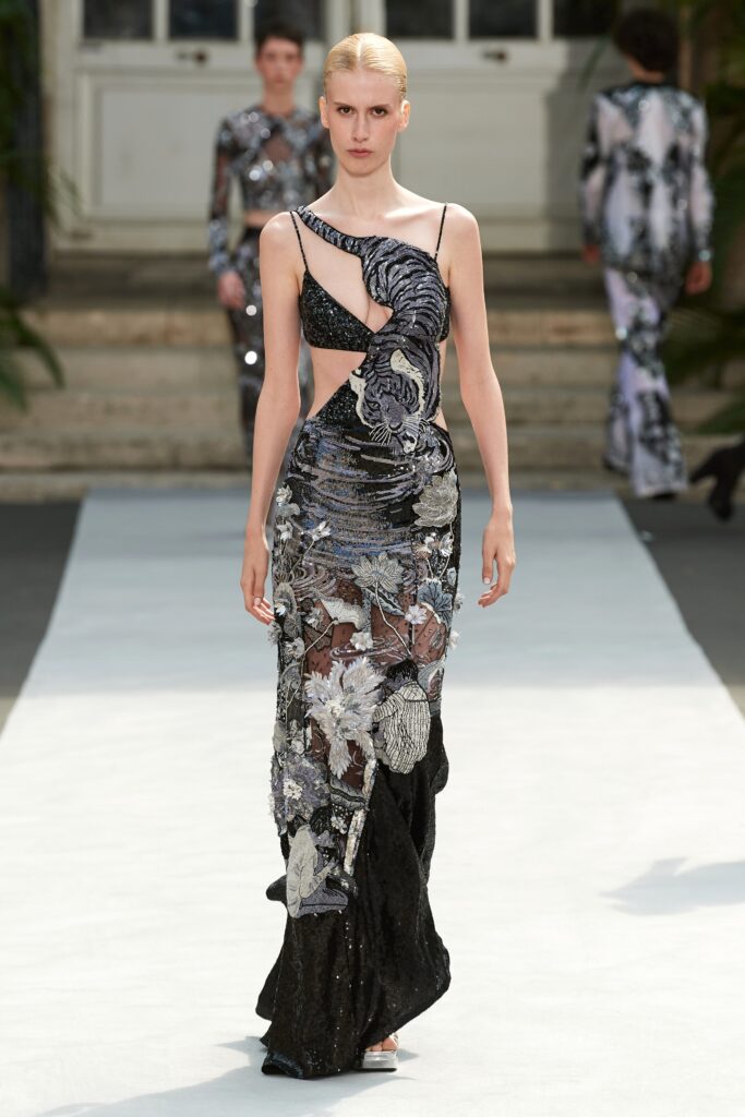 A fitted black and multicolor sleeveless dress with an asymmetric design and embroidered details.