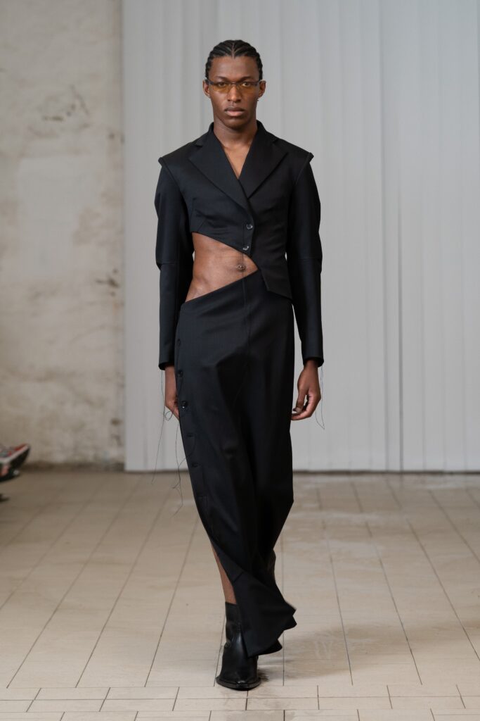 A fitted black dress with an asymmetric design and a tailored jacket overlay.