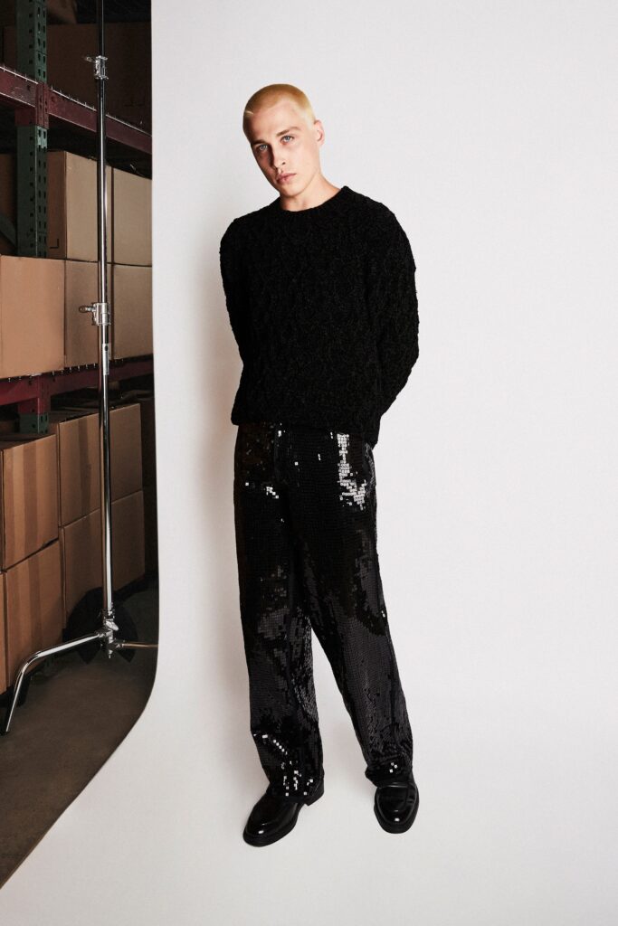 A relaxed black sweater with long sleeves paired with high-waisted sequin pants.