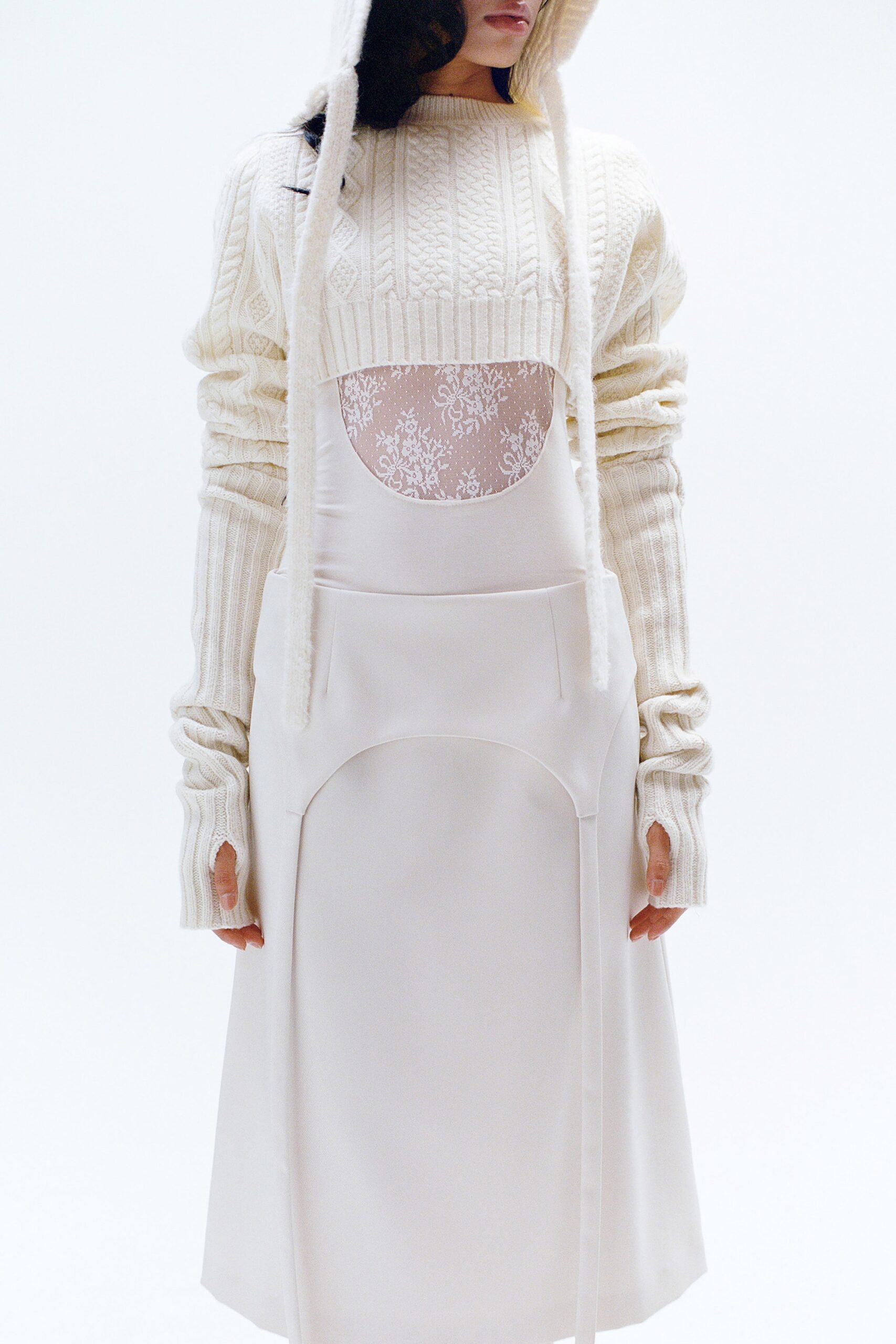 A fitted white dress layered with a long-sleeve high-neck sweater.