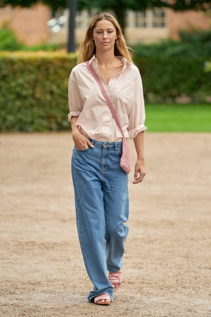 A relaxed pink collared shirt paired with relaxed-fit blue denim pants.