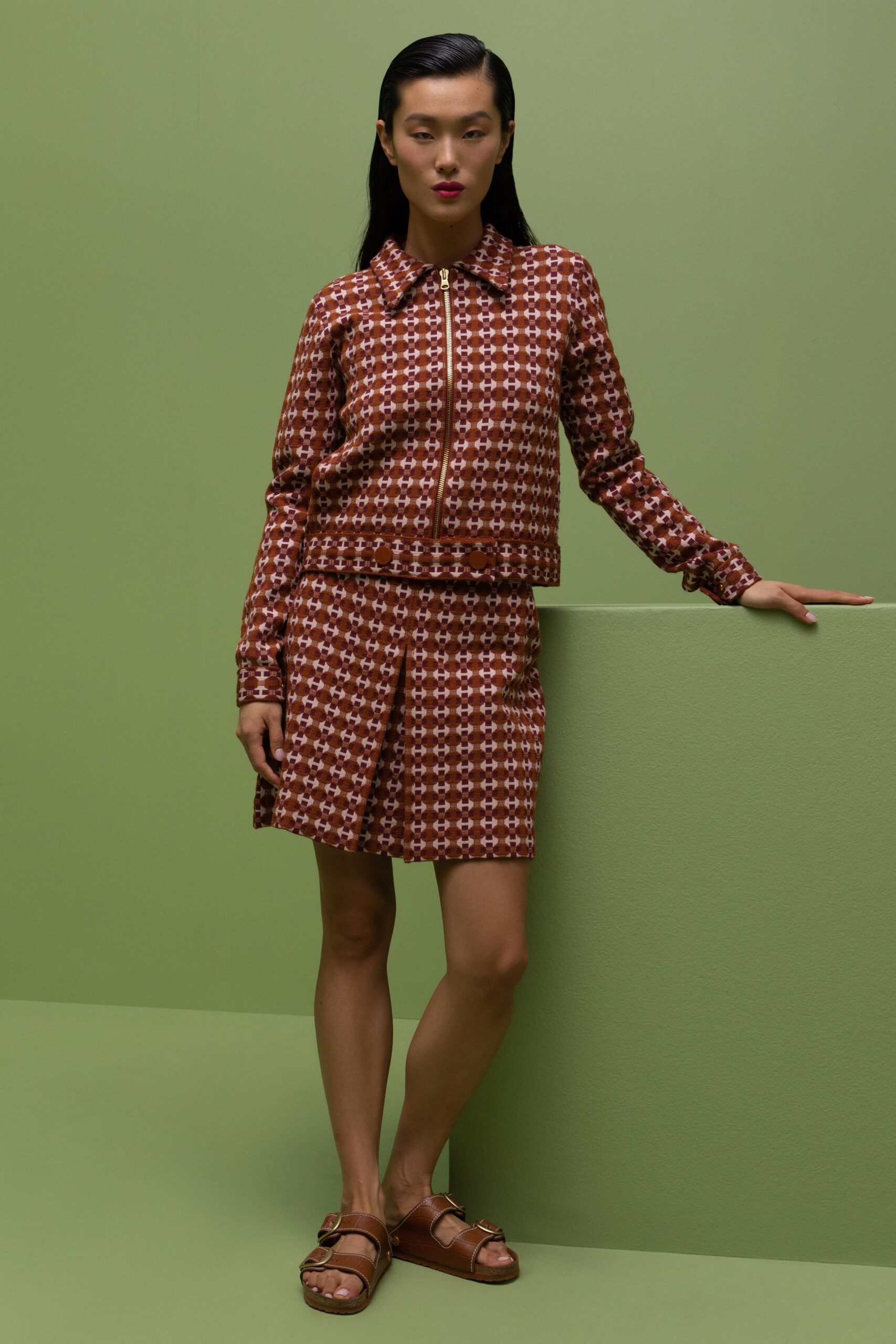 A fitted brown printed jacket with a collared neckline paired with an asymmetric skirt.