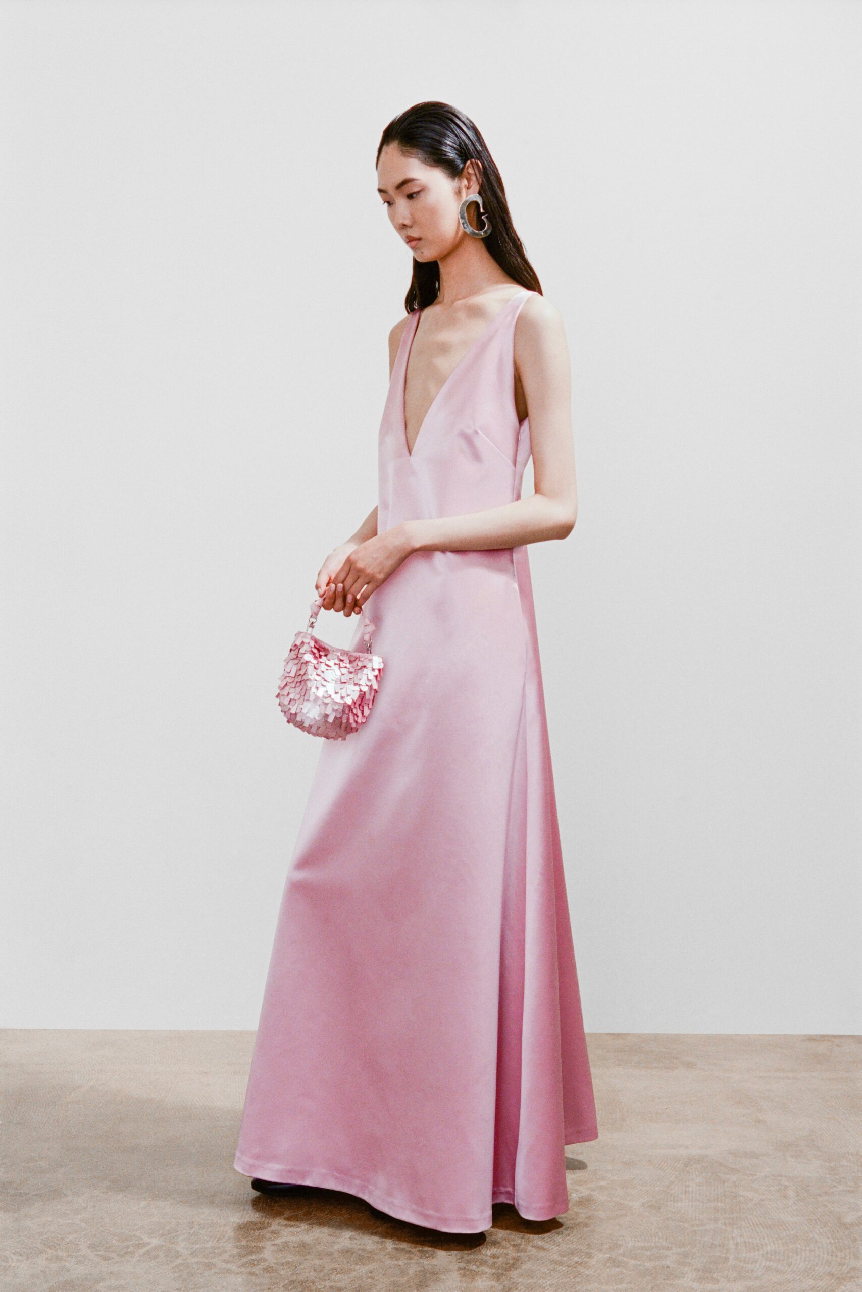 A fitted pink silk sleeveless dress with a V-neckline and A-line silhouette.