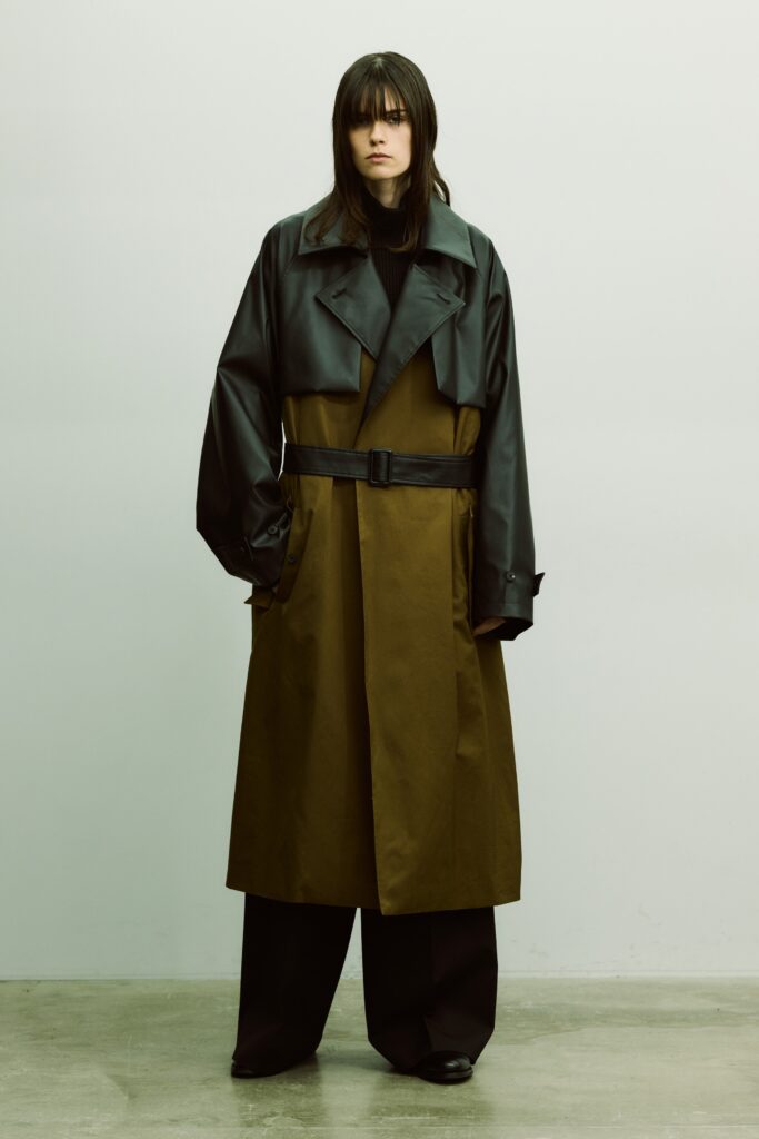 An oversized belted coat in black and brown paired with wide-leg pants.