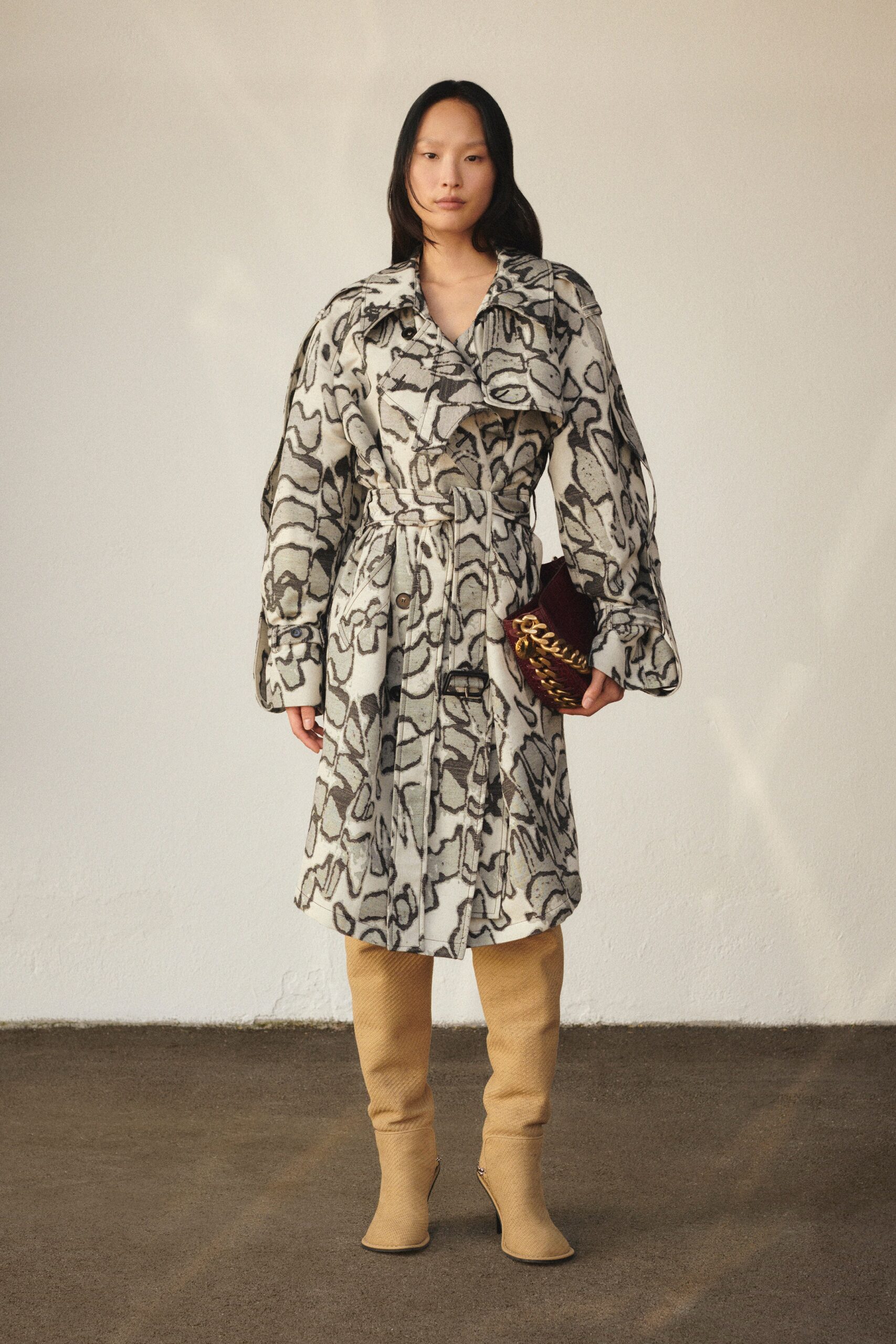 A relaxed beige coat with long sleeves, a collared neckline, and a printed design.
