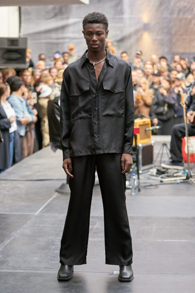 A relaxed black silk long-sleeve shirt with collared design paired with straight-leg pants.