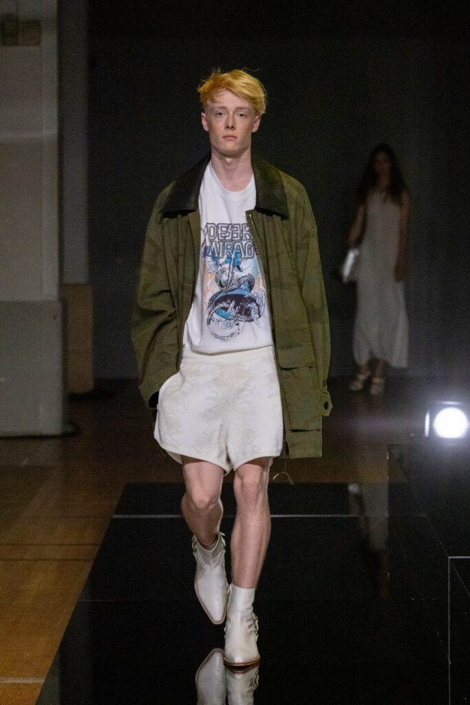 A relaxed green jacket with a printed t-shirt and white shorts for a casual look.