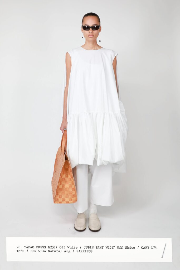 A relaxed white sleeveless tiered dress paired with loose-fitting pants.