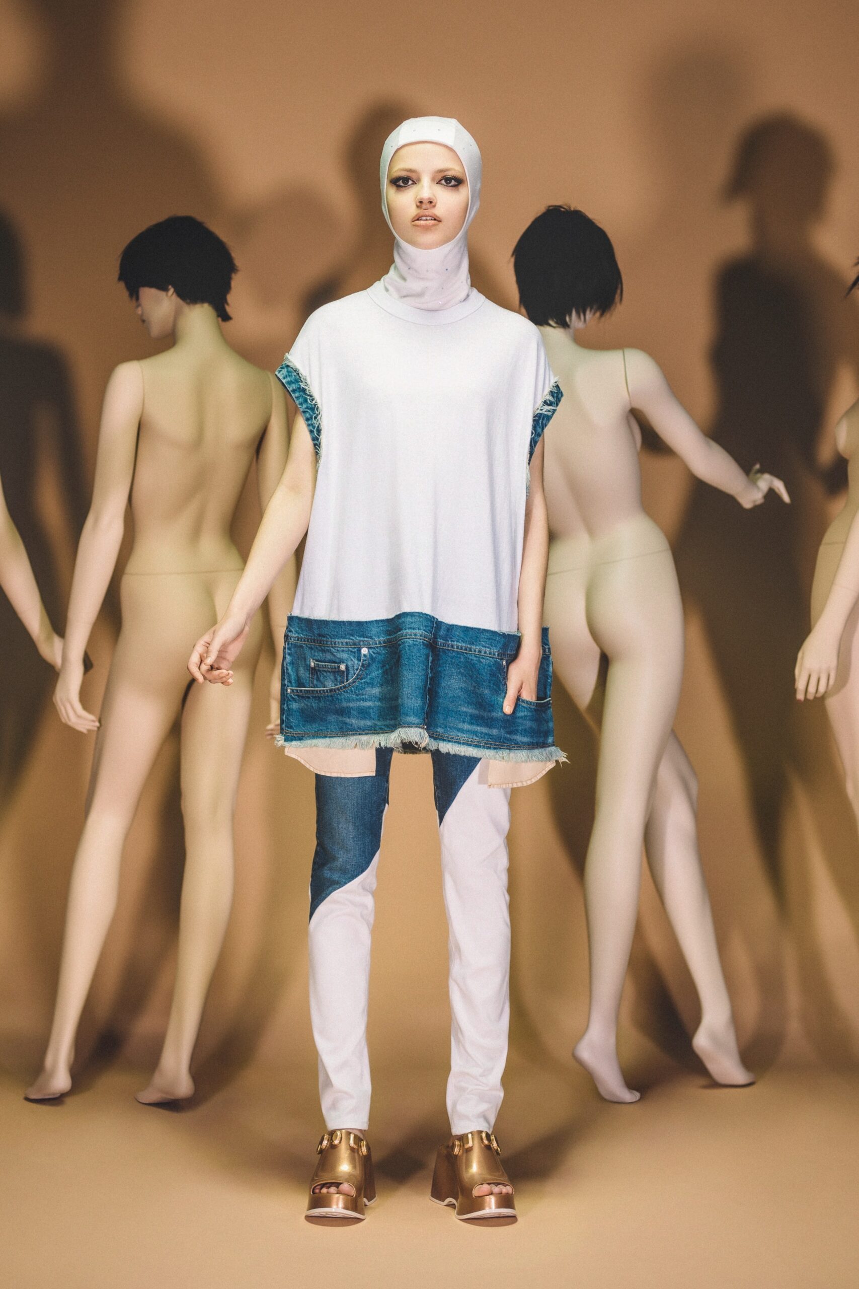 A relaxed white cotton top with short sleeves and high neck, paired with blue denim pants featuring fringed details.
