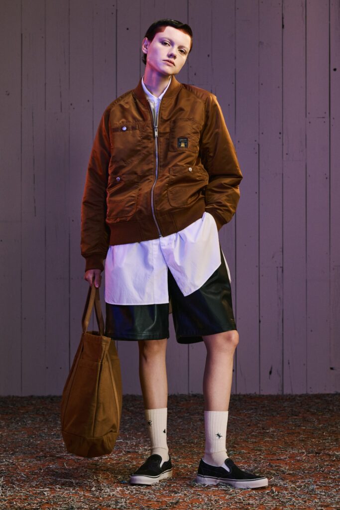 A relaxed brown cotton jacket paired with black leather shorts featuring a straight-leg design.