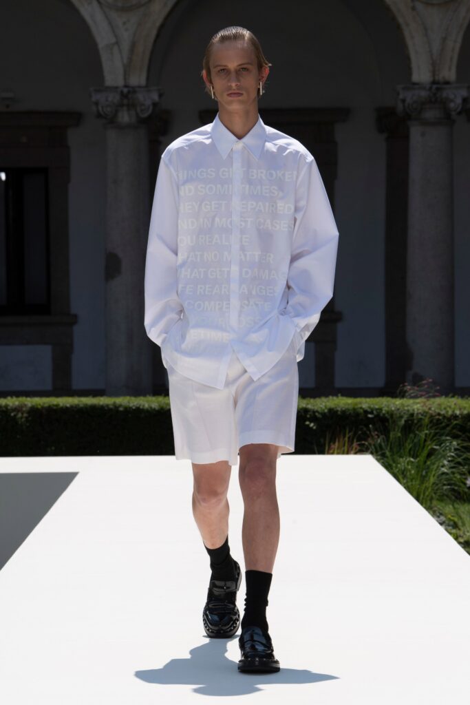 A relaxed white long-sleeve collared shirt with printed details paired with matching shorts.