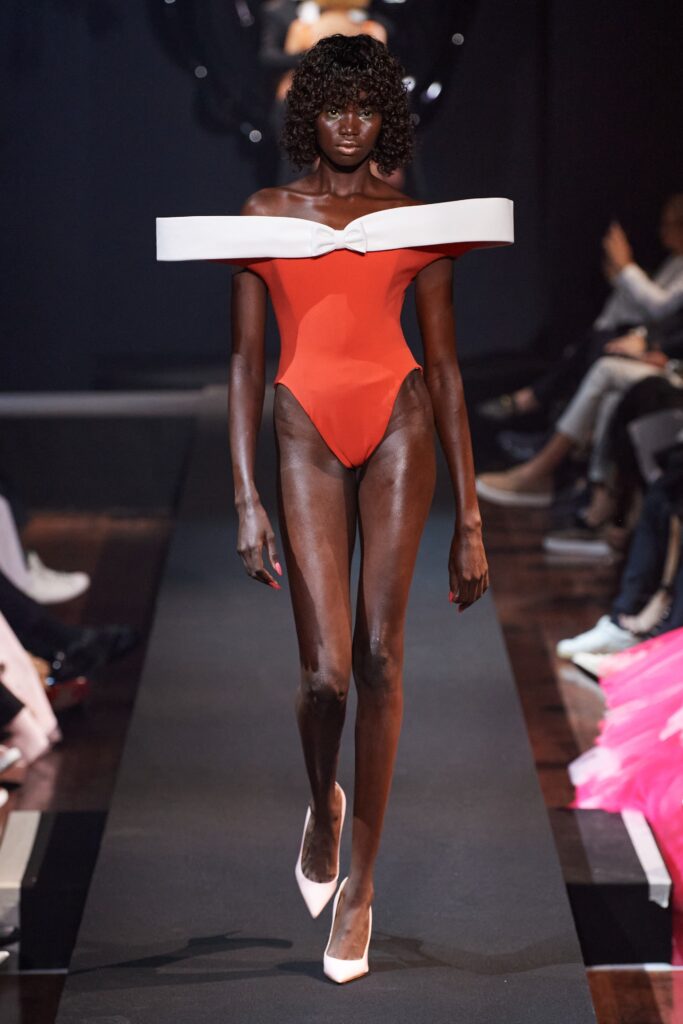 A fitted red strapless swimsuit with an asymmetric design detail.