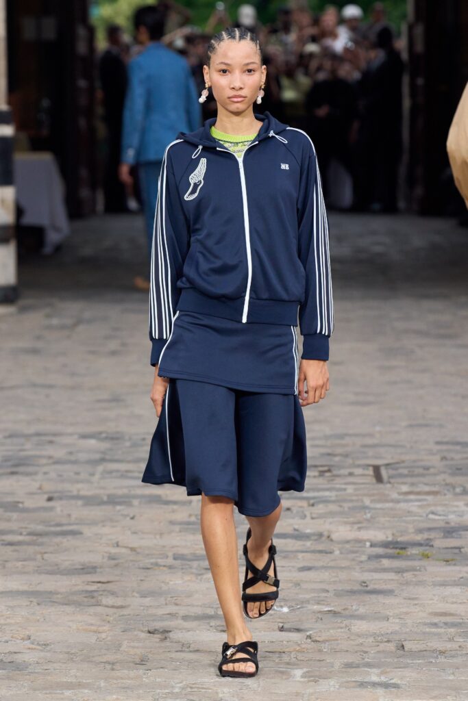 A fitted navy dress paired with a long-sleeve collared jacket featuring an asymmetric design.