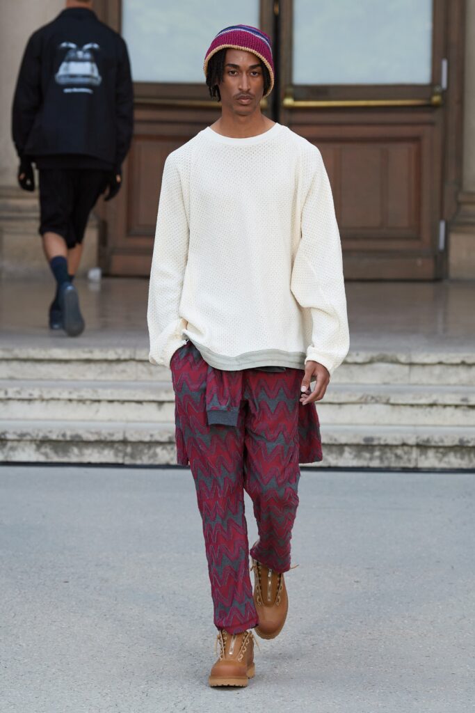 A relaxed white long-sleeve sweater paired with red printed pants for a casual look.