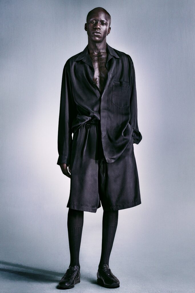 A relaxed black silk long-sleeve shirt with matching shorts, featuring a collared design and buttoned detail.