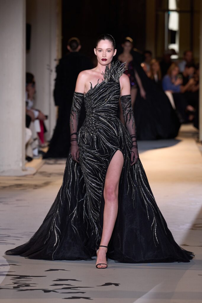 A fitted black silk gown with an asymmetric design and a high slit.