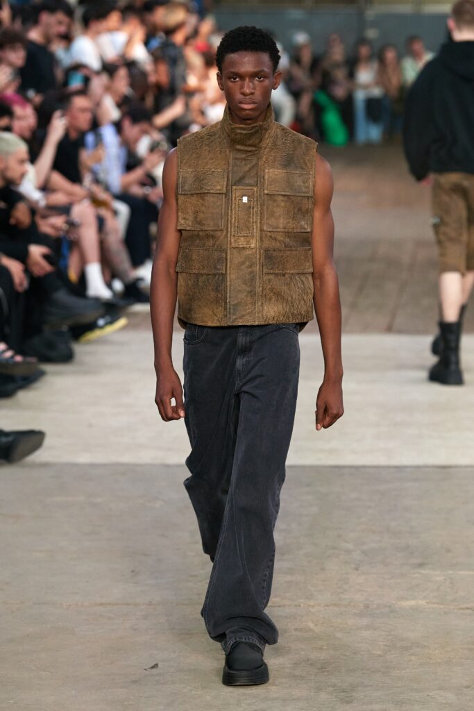A relaxed brown leather sleeveless vest paired with wide-leg black denim pants.