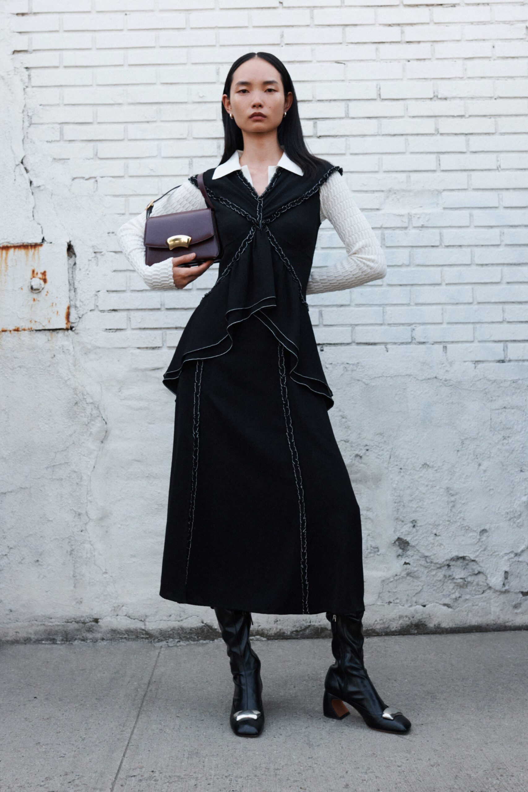 A fitted black dress with long sleeves, a V-neckline, and an asymmetric design.