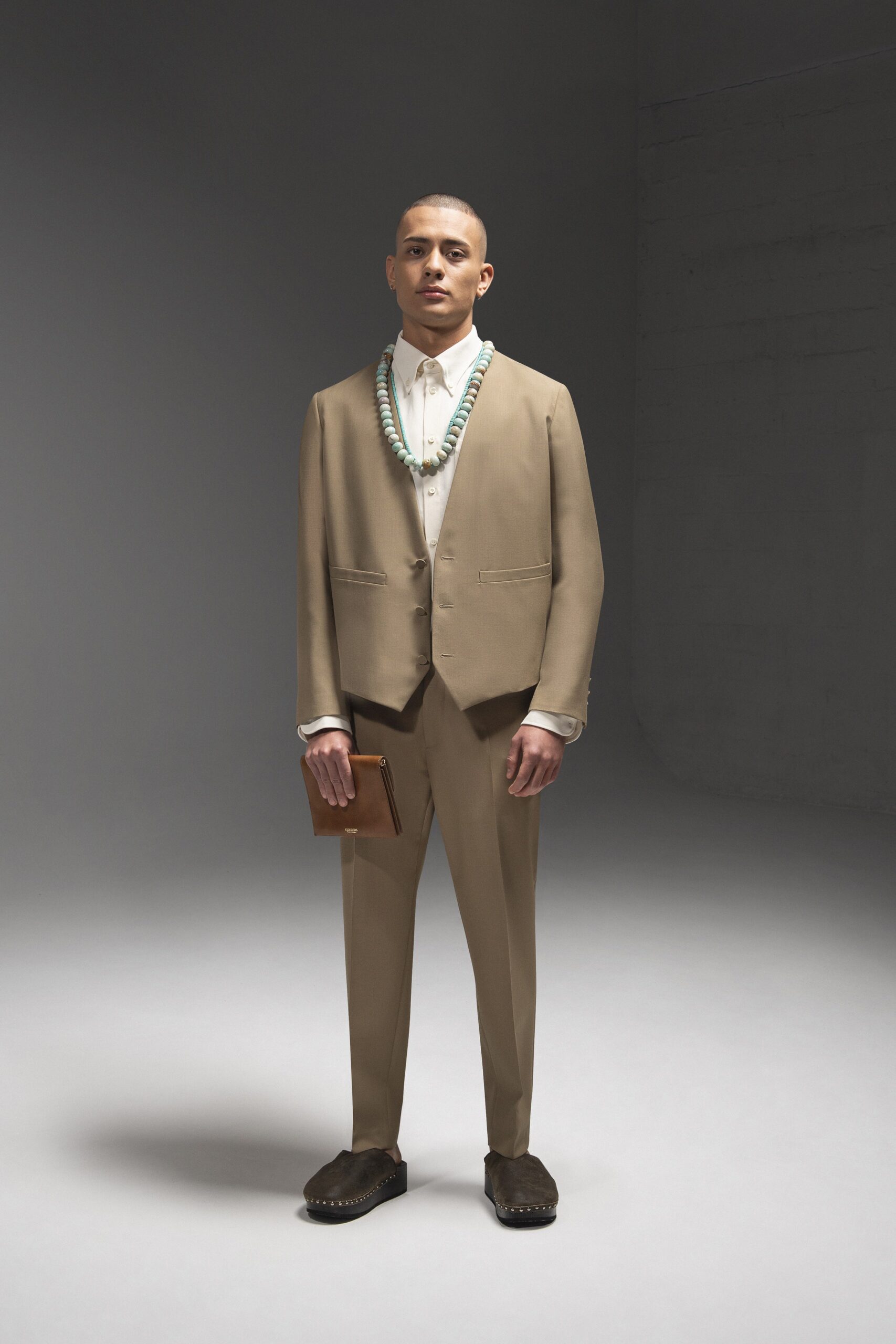 A tailored beige suit with long sleeves and a collared shirt, featuring button details.