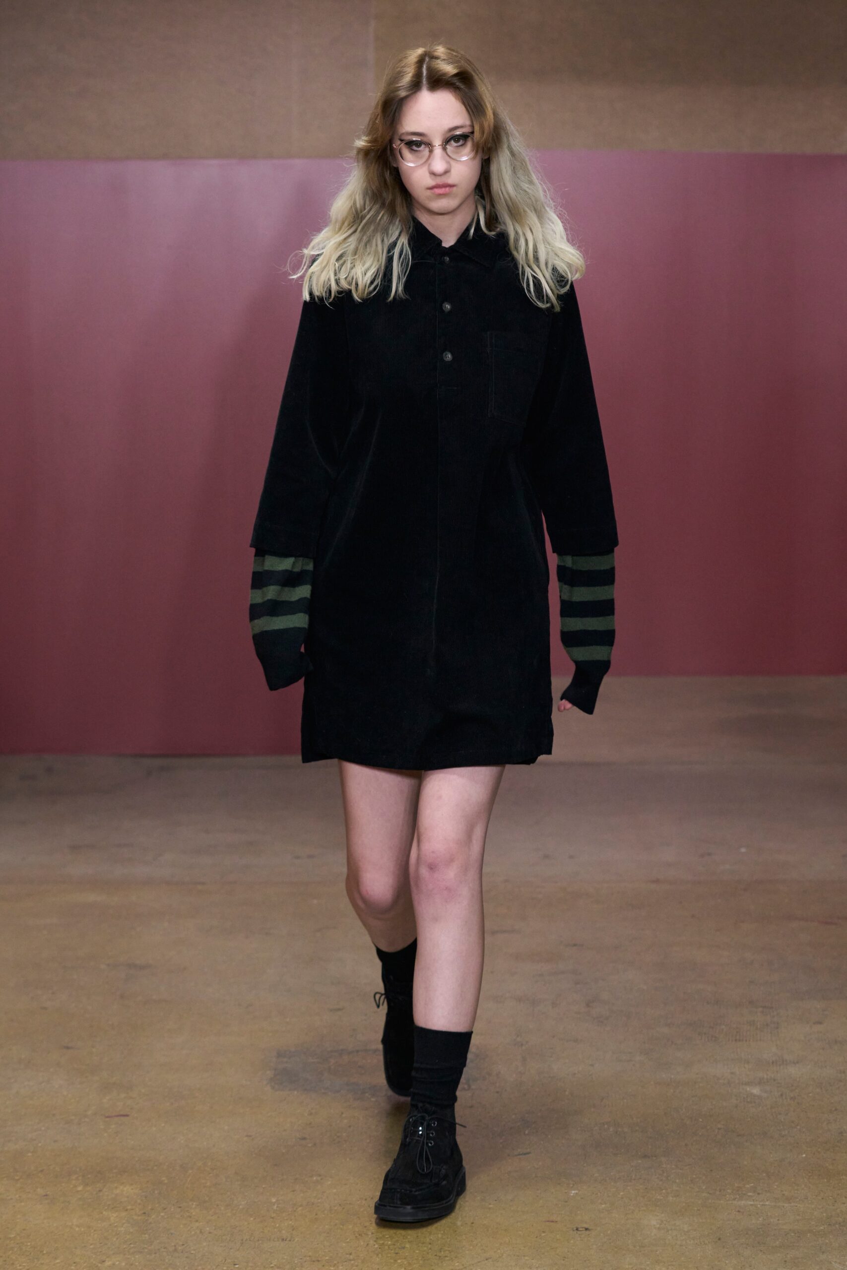 A relaxed black dress with long sleeves and a collared neckline, featuring button details.