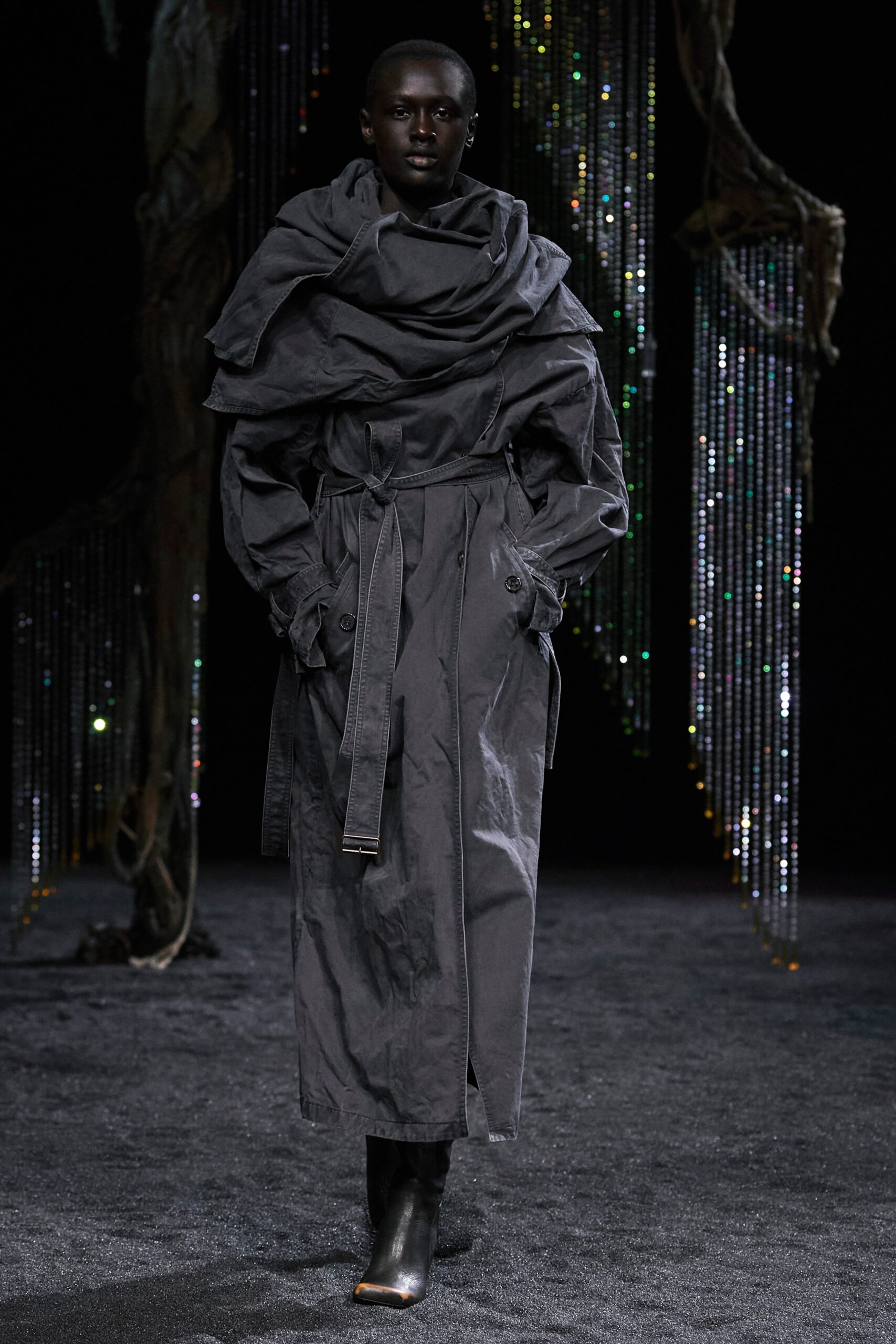 A relaxed black cotton coat with long sleeves and a layered design detail.