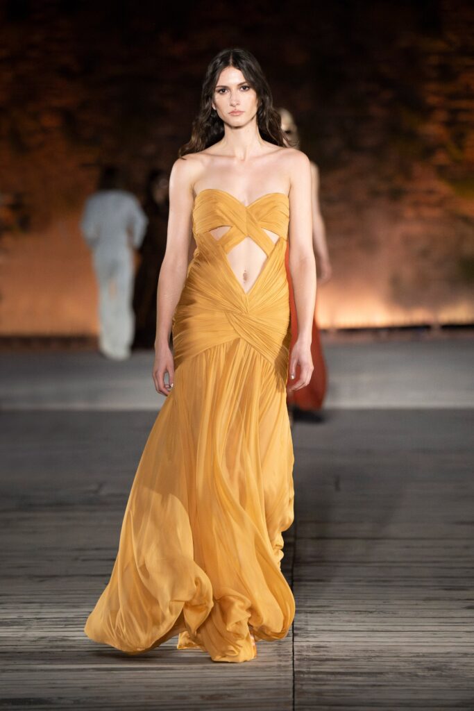 A fitted yellow silk gown with a sleeveless design and draped details.