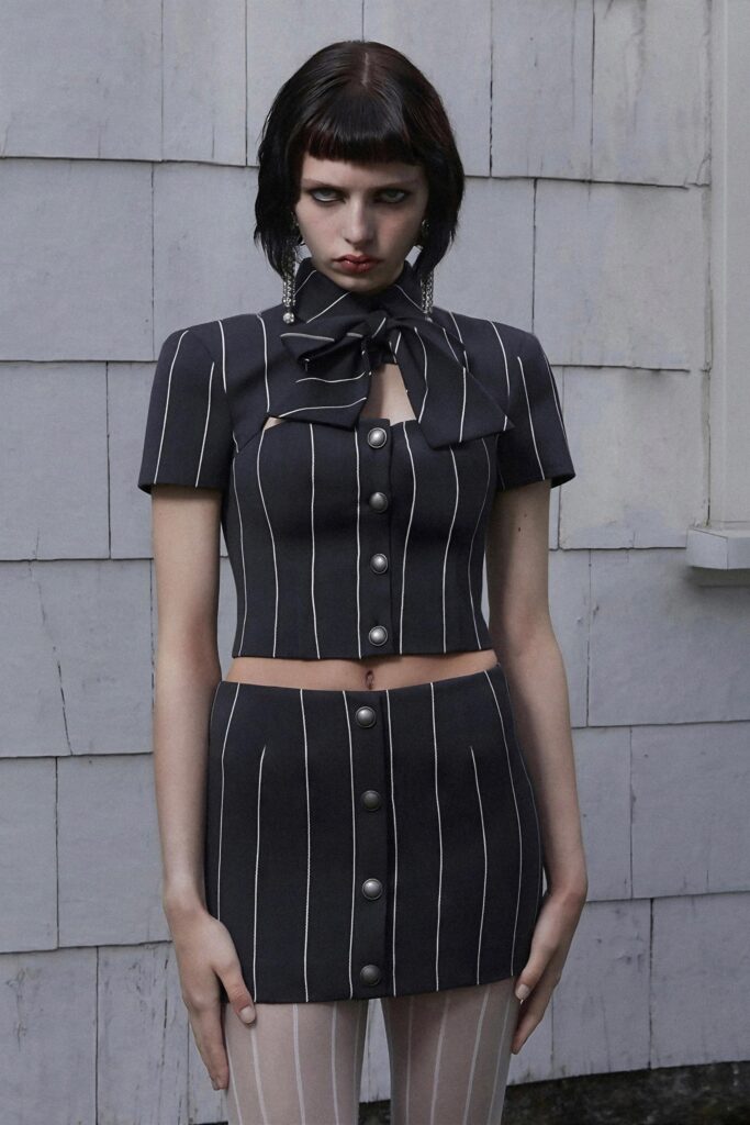 A fitted black cotton top with short sleeves and a collared design, paired with a matching striped skirt.
