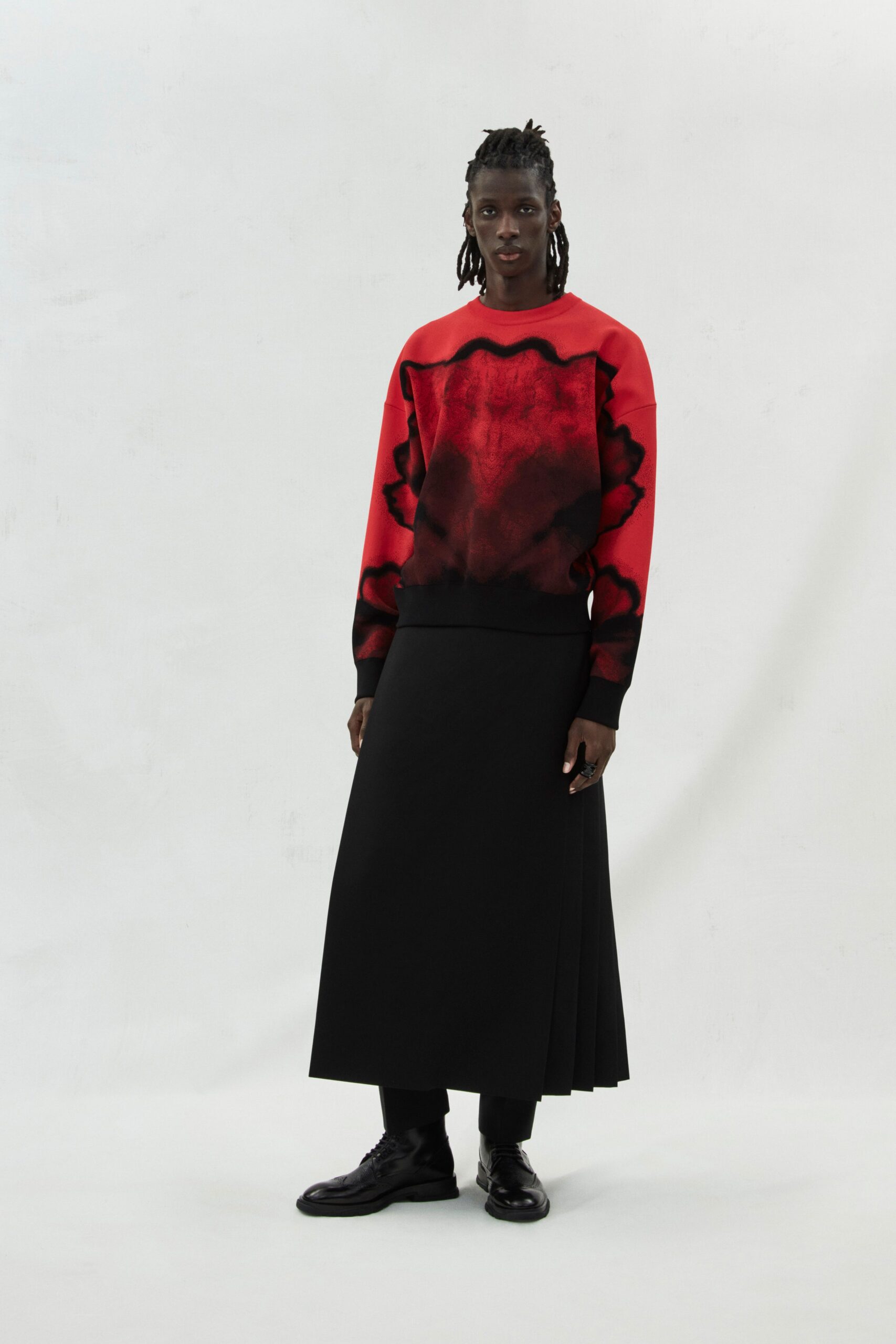 red printed relaxed sweater and black pleated skirt