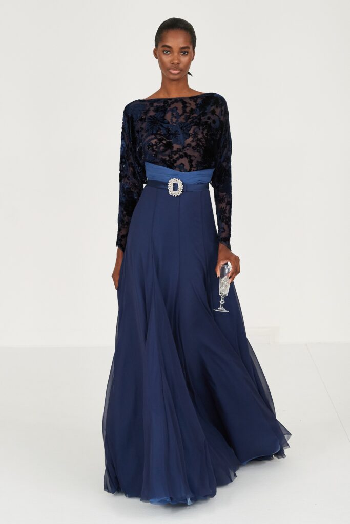 A fitted blue silk long-sleeve gown with pleated details and a high neckline.