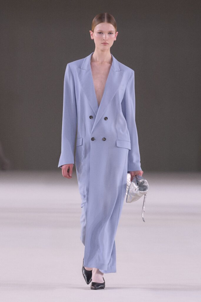 A fitted blue silk dress with a deep V-neckline and straight-leg silhouette.
