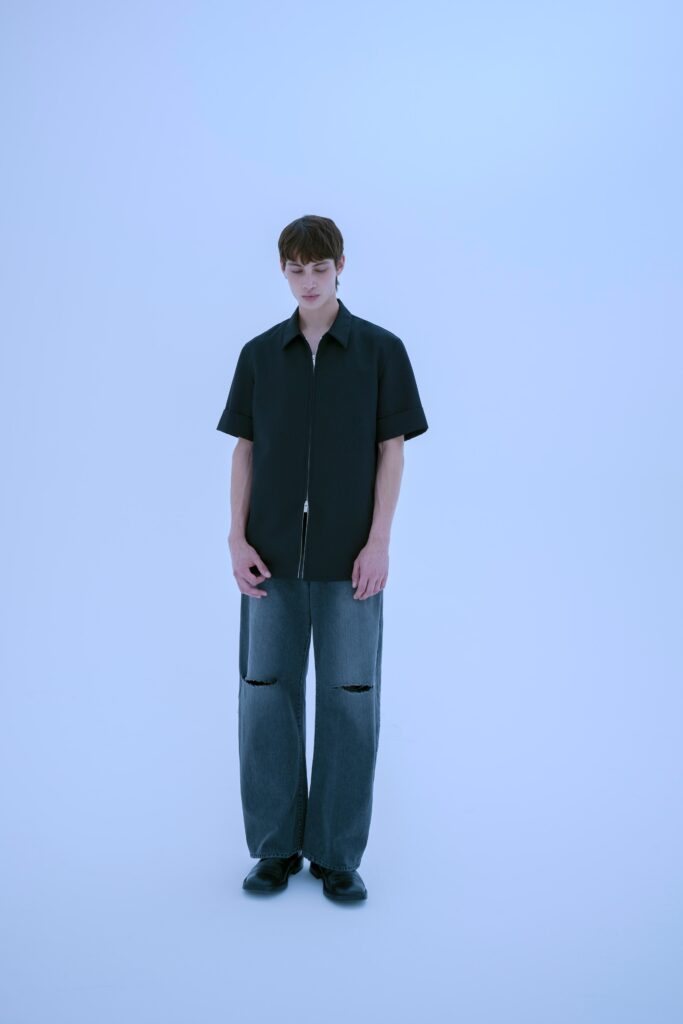 A relaxed black shirt paired with wide-leg gray denim pants, creating a modern casual look.