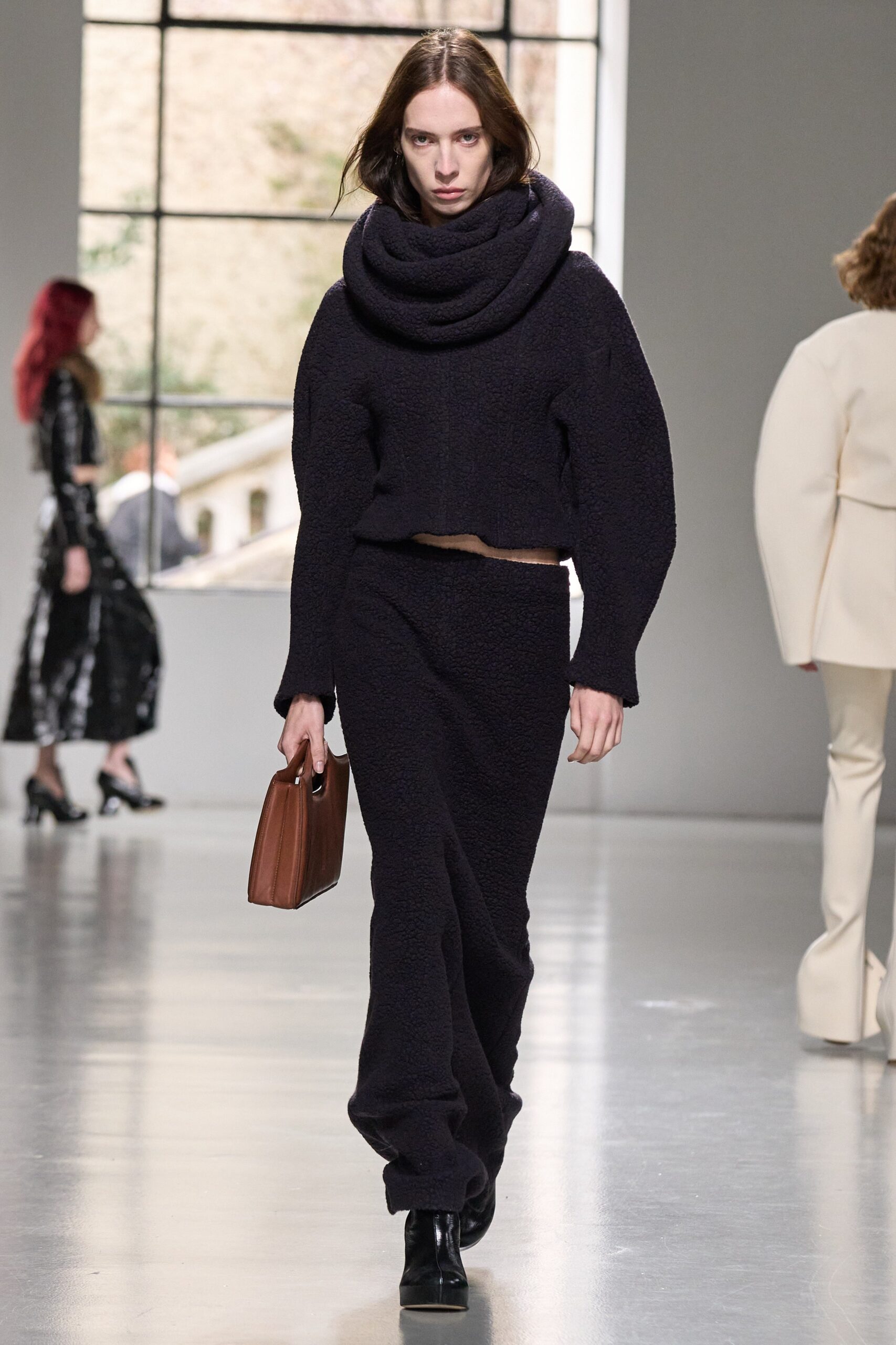 A relaxed black wool long-sleeve top with a high-neck paired with a matching skirt.