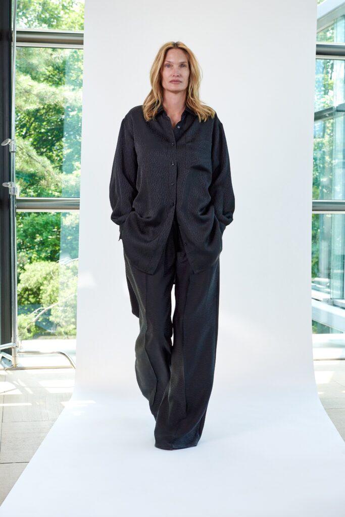 A relaxed black shirt with long sleeves and a collared neckline paired with straight-leg pants.