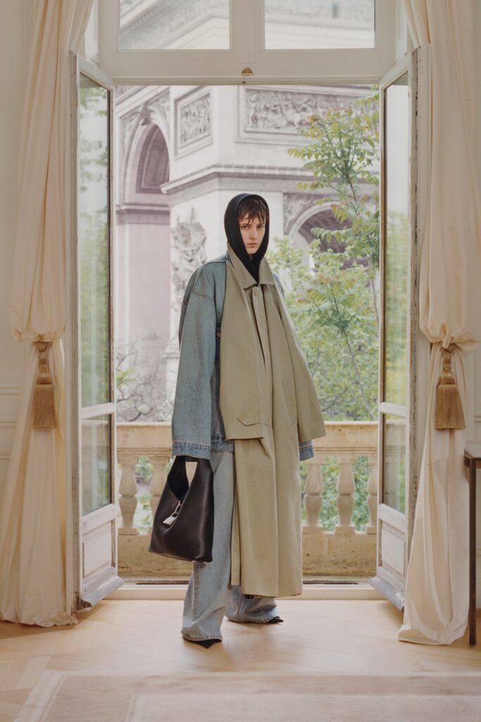 An oversized beige coat paired with blue denim pants, featuring a layered look and long sleeves.