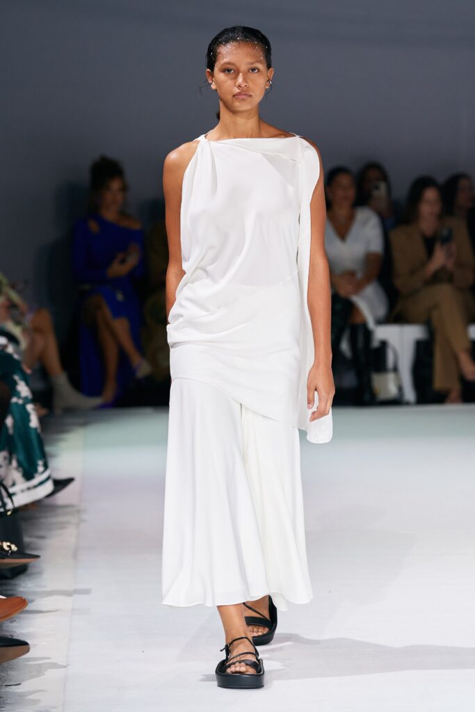 A relaxed white sleeveless dress with a high neckline and draped design.