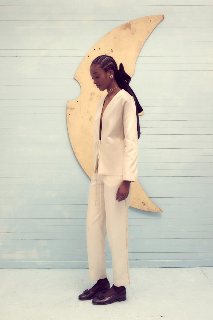 A fitted beige silk jacket with long sleeves and a V-neck, paired with matching pants.