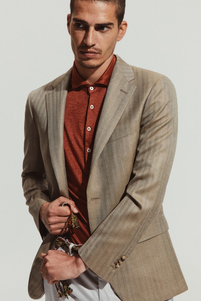 A fitted beige striped blazer paired with a red collared shirt, creating a stylish look.