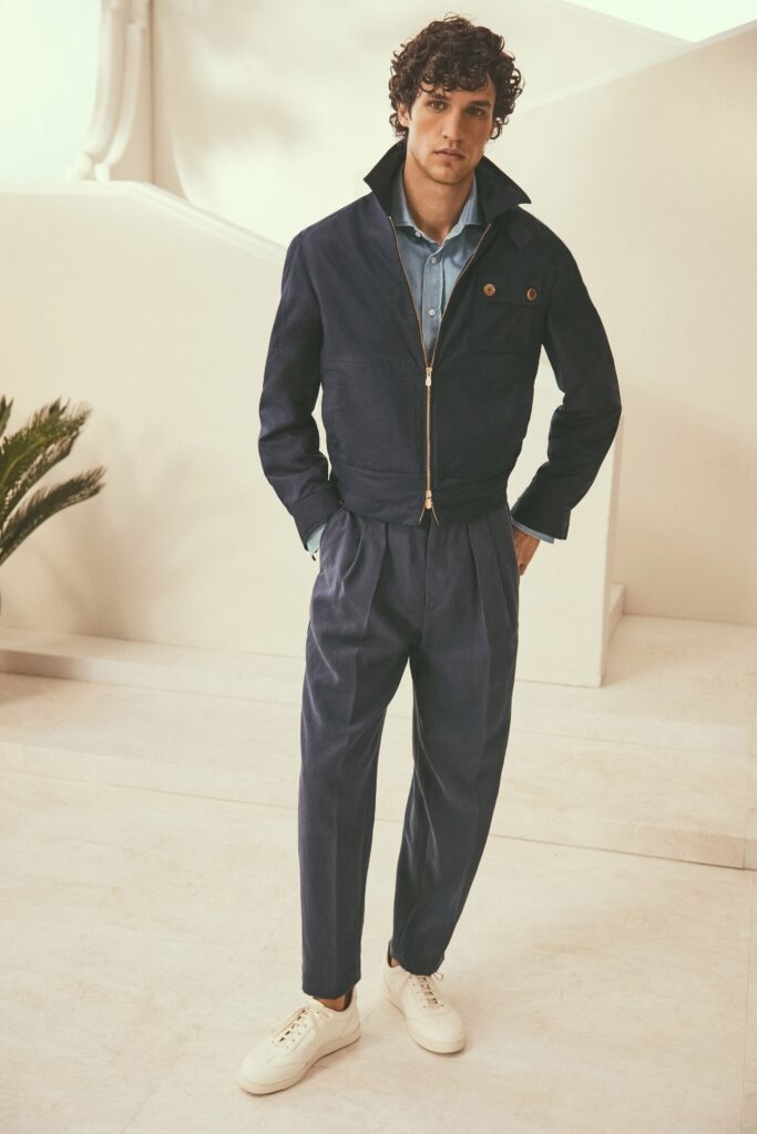 A relaxed navy cotton jacket with a collared neckline paired with pleated pants.