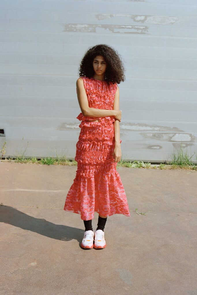 A fitted red cotton sleeveless dress with a high neckline and tiered design.