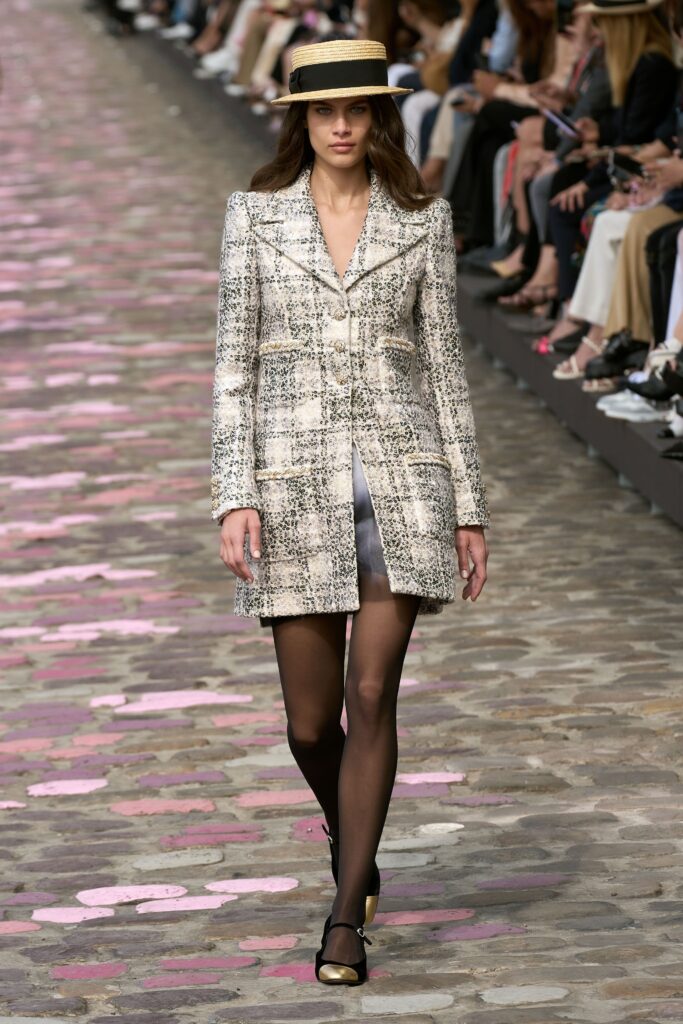 A tailored beige tweed coat with long sleeves and a collared design featuring a checked pattern.
