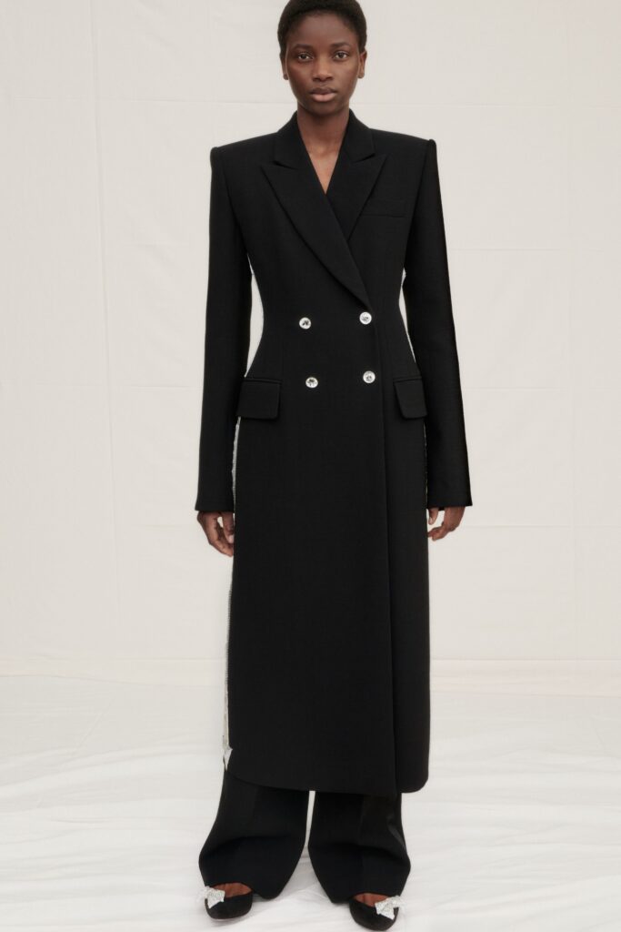 A tailored black wool coat with long sleeves and a double-breasted design paired with straight-leg pants.