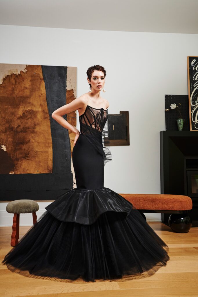 A fitted black silk strapless dress with a V-neckline and flared silhouette.