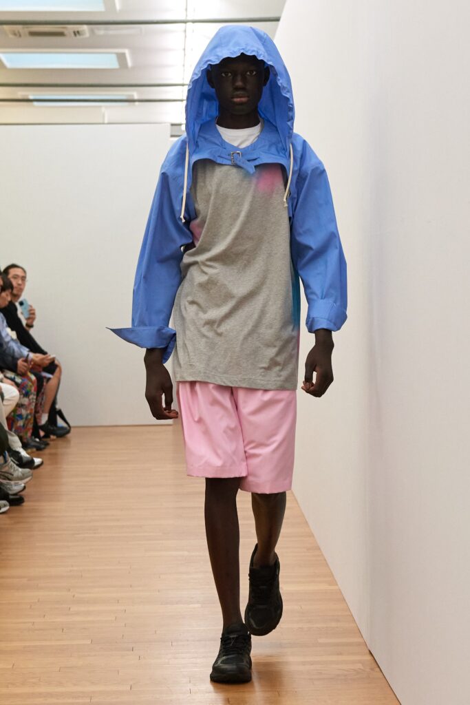 A relaxed fit blue and gray color-blocked hoodie paired with pink shorts.