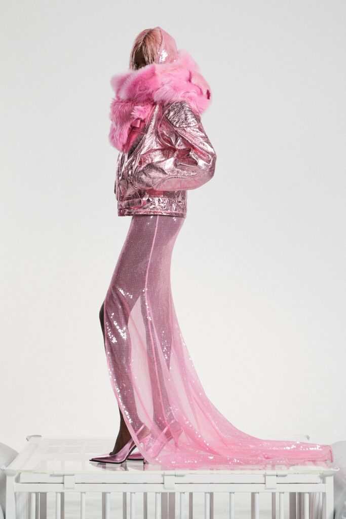 A fitted pink metallic dress with a V-neckline and asymmetric slit detail.