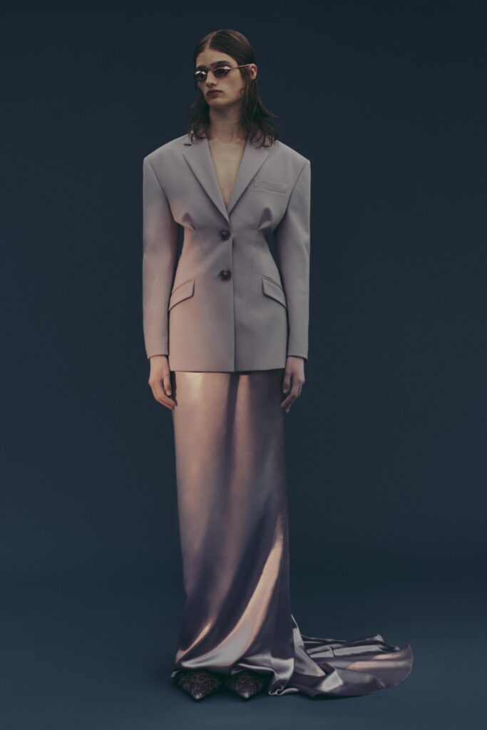 A fitted gray silk blazer paired with a silver asymmetric skirt, creating a sophisticated look.