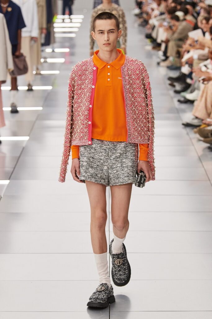 A relaxed pink jacket with a collared short-sleeve design paired with gray shorts.