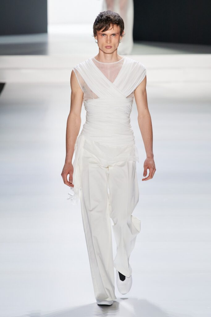 A fitted white sleeveless top with a V-neck and asymmetric design paired with matching pants.